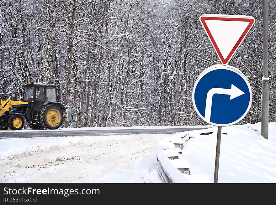 Give a way sign and tractor cleaning snow