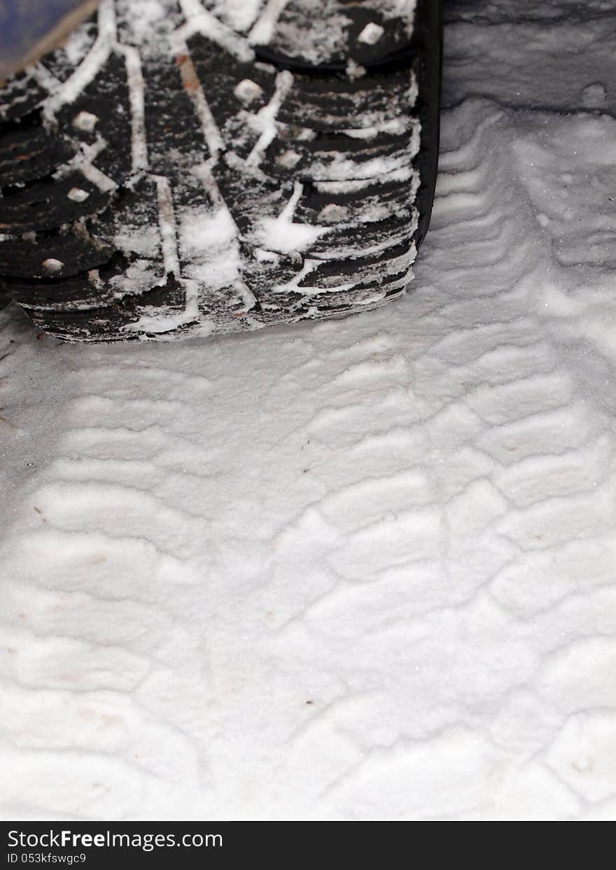 Winter tire tracks in snow, closeup, focus on tire