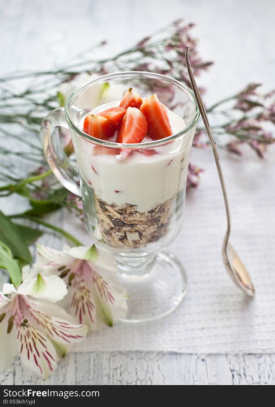 Muesli with yogurt ant strawberries on wooden background