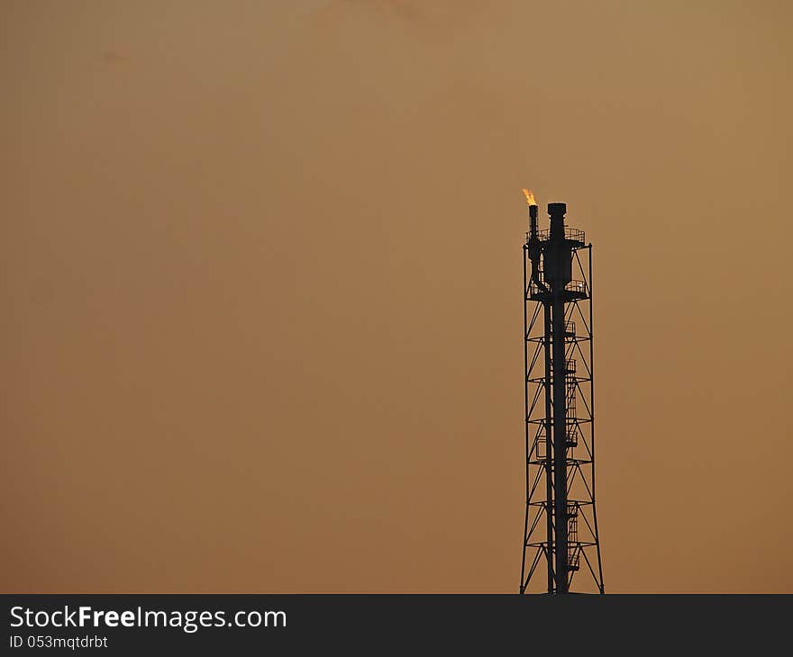 High tower of refinery in evening sky