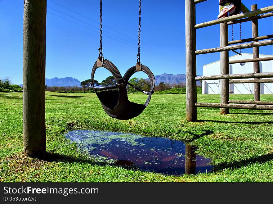 Swing in children playground against mountains. Shot in wine farms between Stellenbosch and Cape Town, Western Cape, South Africa.