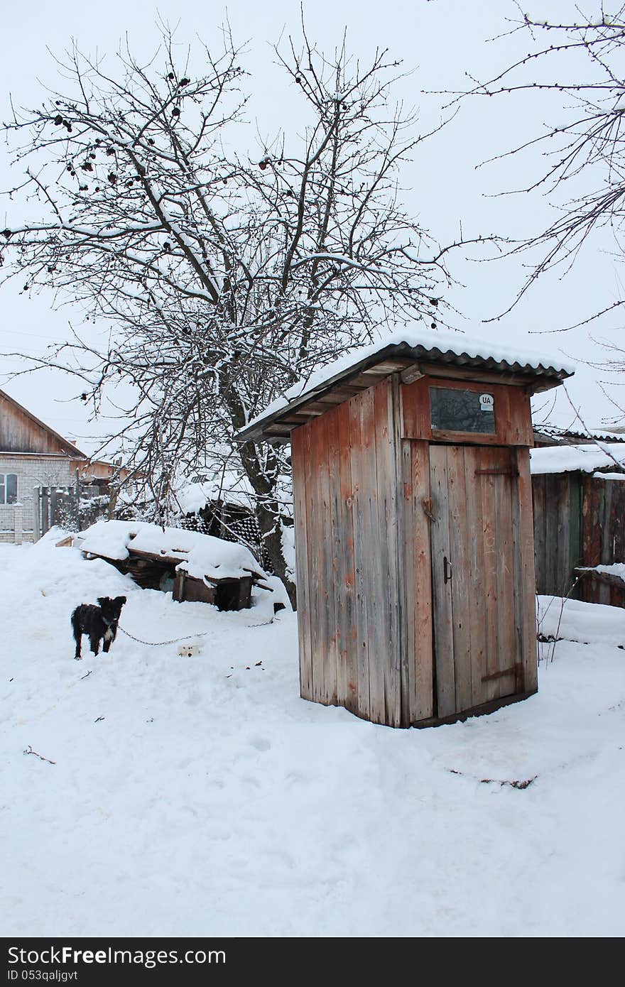 Rural toilet and black dog in winter. Rural toilet and black dog in winter