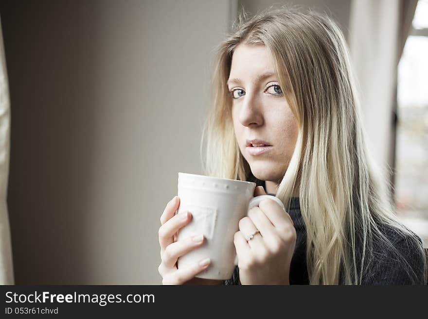 Pretty young blonde woman drinking her morning coffee. Pretty young blonde woman drinking her morning coffee.