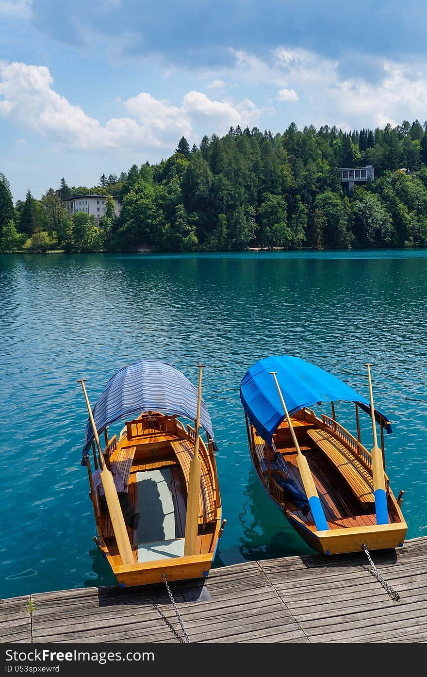 Two row boats floating empty tied to a dock on a lake. Two row boats floating empty tied to a dock on a lake