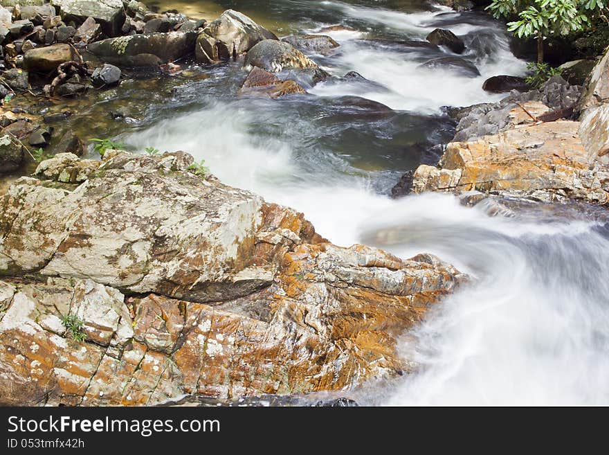 The flowing of waterfall  on big rock that be full of moss