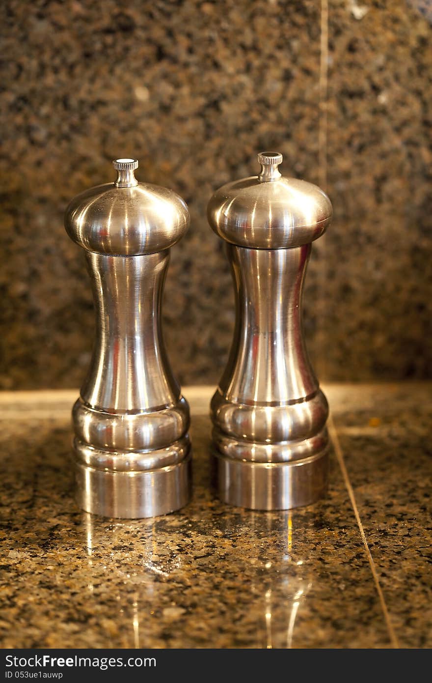 Salt and pepper shakers on a granite counter top.