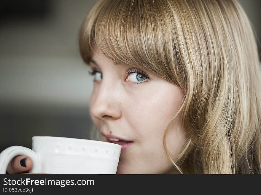 Portrait of a young woman staring straight ahead into the camera holding a cup of coffee. Portrait of a young woman staring straight ahead into the camera holding a cup of coffee.