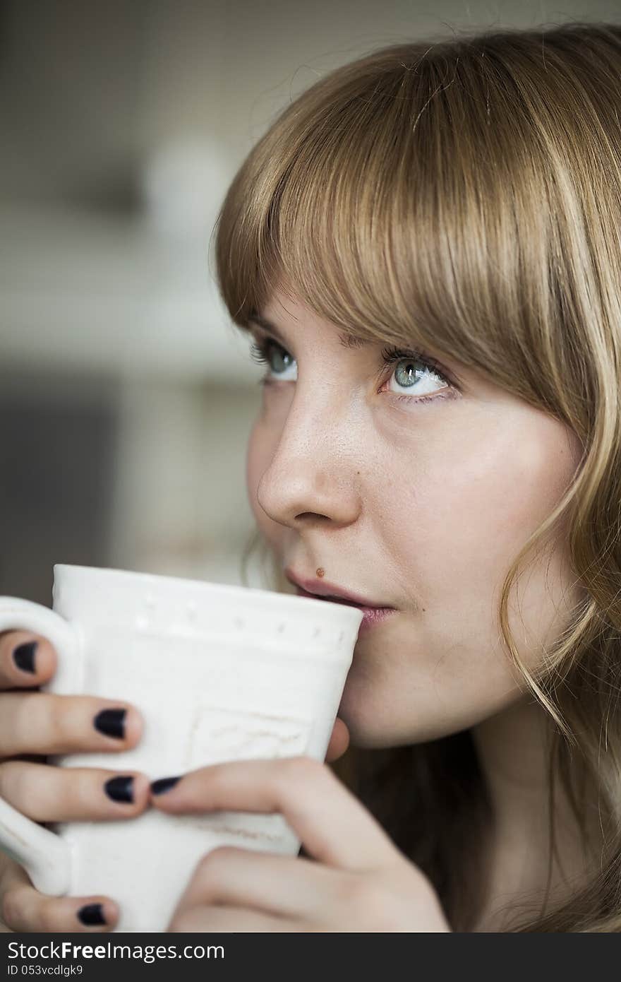 Portrait of a young woman looking up while holding a cup of coffee. Portrait of a young woman looking up while holding a cup of coffee.