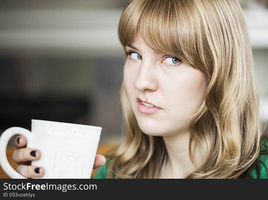 Portrait of a young woman making an ugly face and holding a cup of coffee. Portrait of a young woman making an ugly face and holding a cup of coffee.