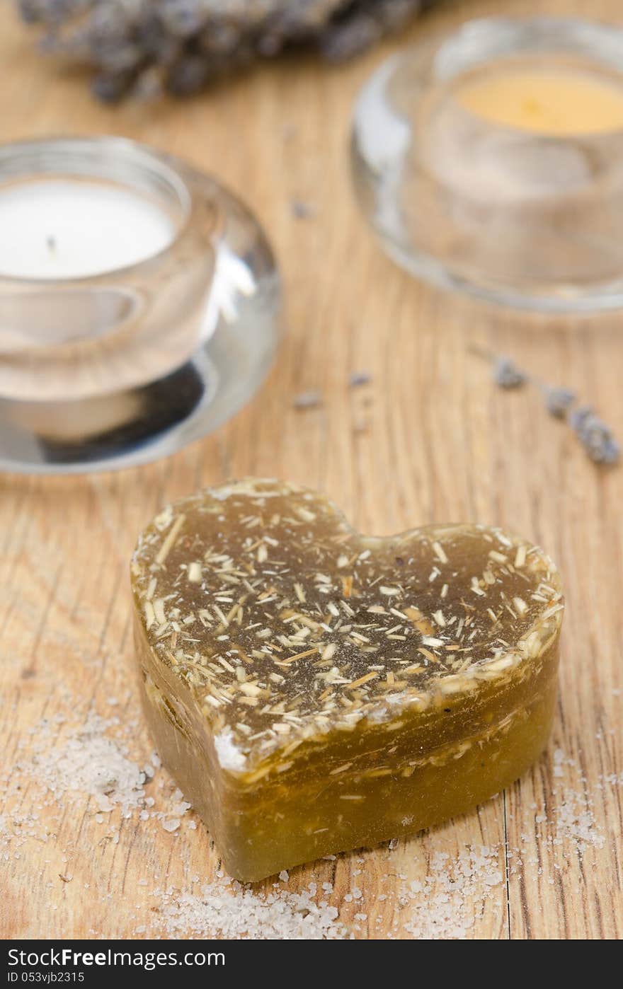 Bath soap with lavender in a heart and candles on wooden table