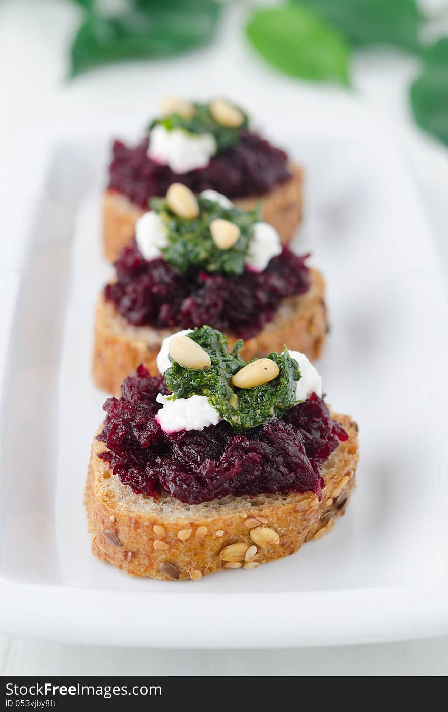 Beet salad with pesto and goat cheese on toasted grain breads on a plate