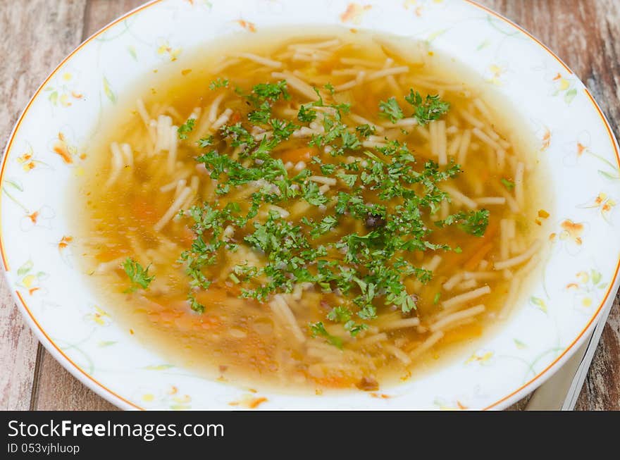 Chicken soup with noodles and carrots closeup top view