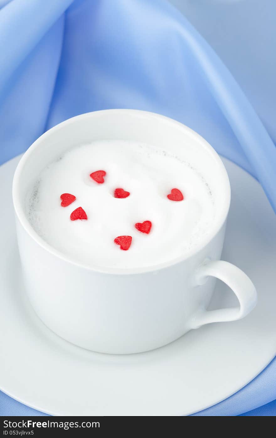 Cup of hot milk foam and sugar hearts