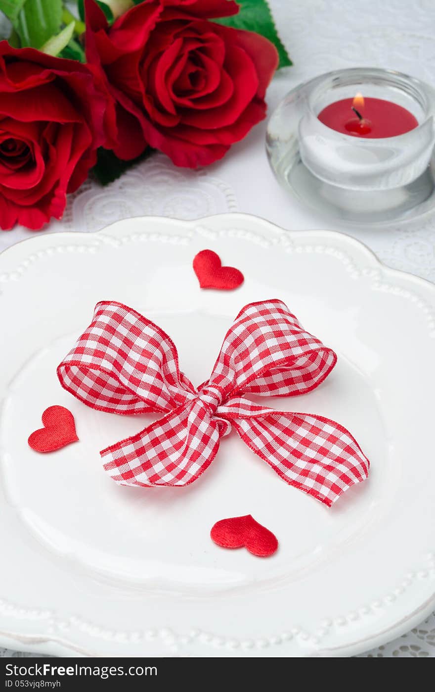 Festive table setting Valentine's Day, hearts, ribbon, roses and candle closeup. Festive table setting Valentine's Day, hearts, ribbon, roses and candle closeup