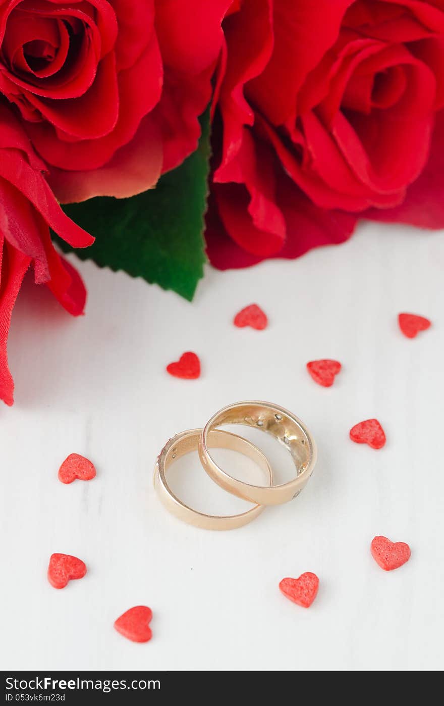 Red roses, rings and sugar hearts for Valentine's Day on a white table. Red roses, rings and sugar hearts for Valentine's Day on a white table