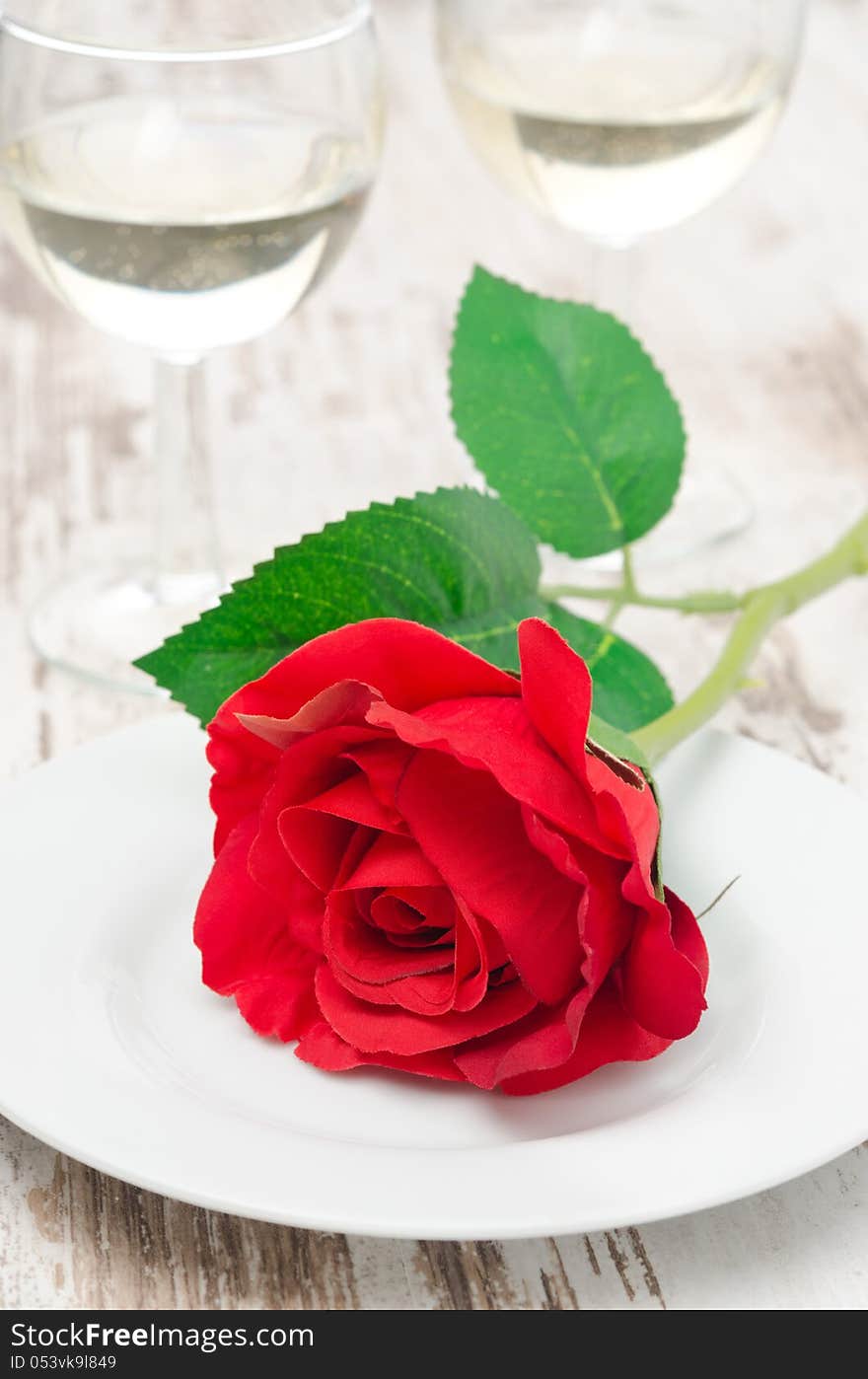 Rose on a plate and glasses of wine on Valentine's Day. Rose on a plate and glasses of wine on Valentine's Day