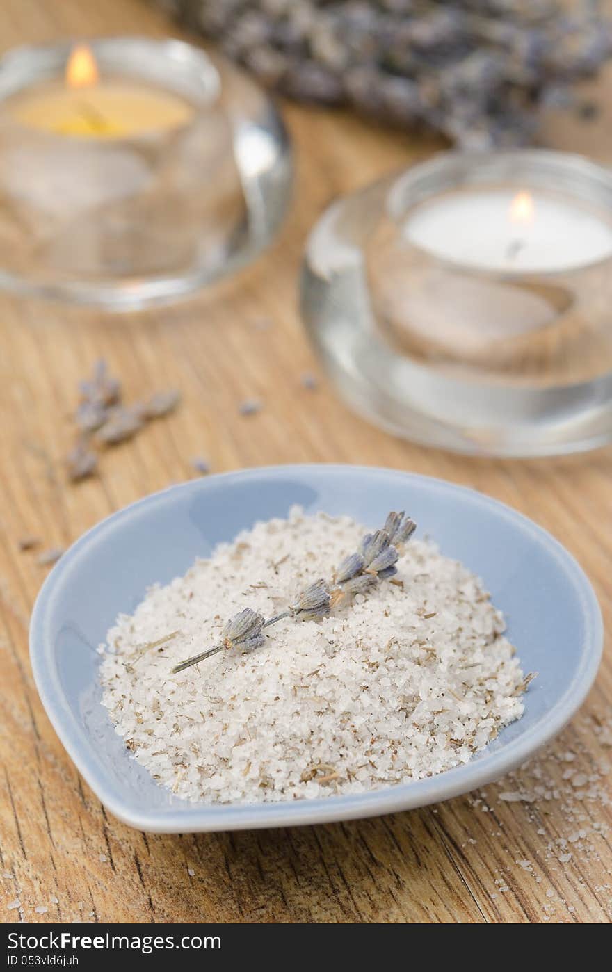 Sea salt with lavender in a blue bowl and two candles on the wooden table. Sea salt with lavender in a blue bowl and two candles on the wooden table