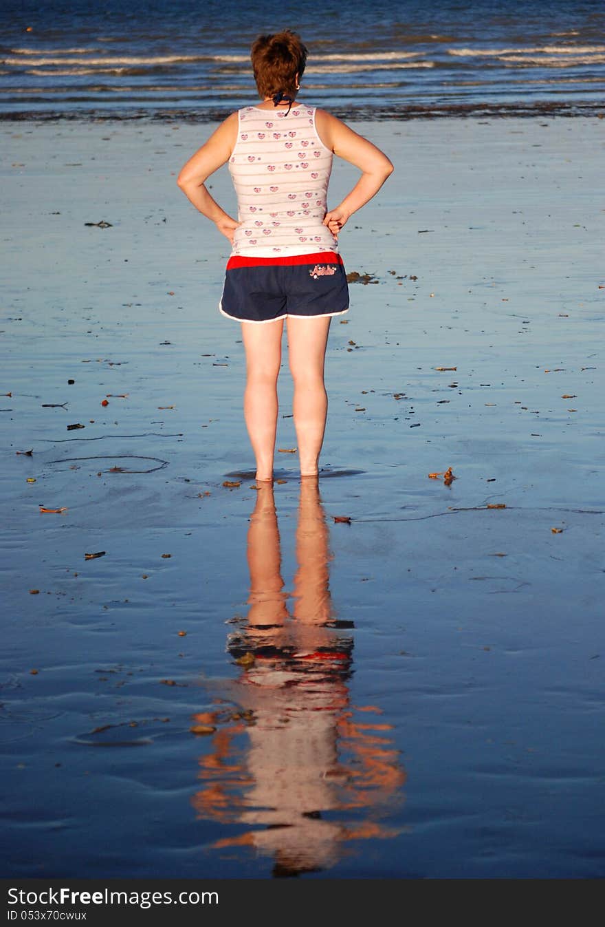 Woman s reflection in wet sand on Australian beach