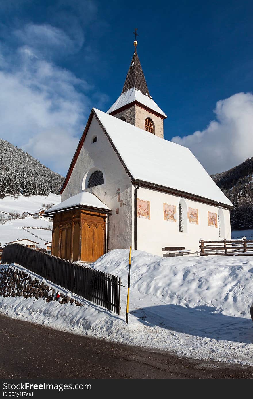 A wintertime view of a small church with a tall steeple