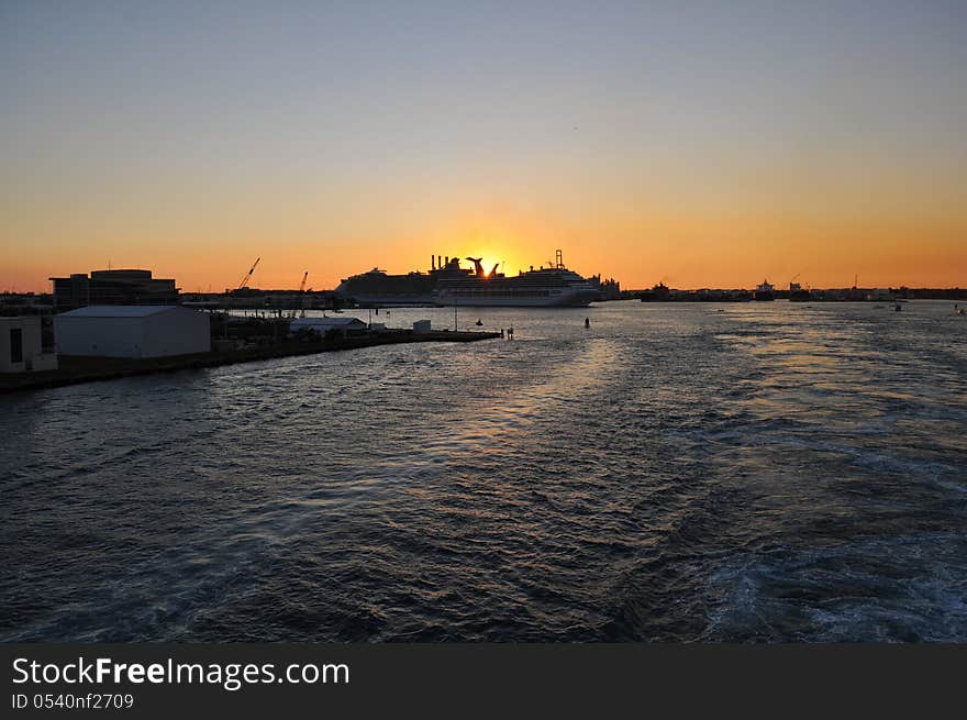 Sun setting over fort lauderdale cruise terminal from a moving cruise ship heading out to sea. Sun setting over fort lauderdale cruise terminal from a moving cruise ship heading out to sea