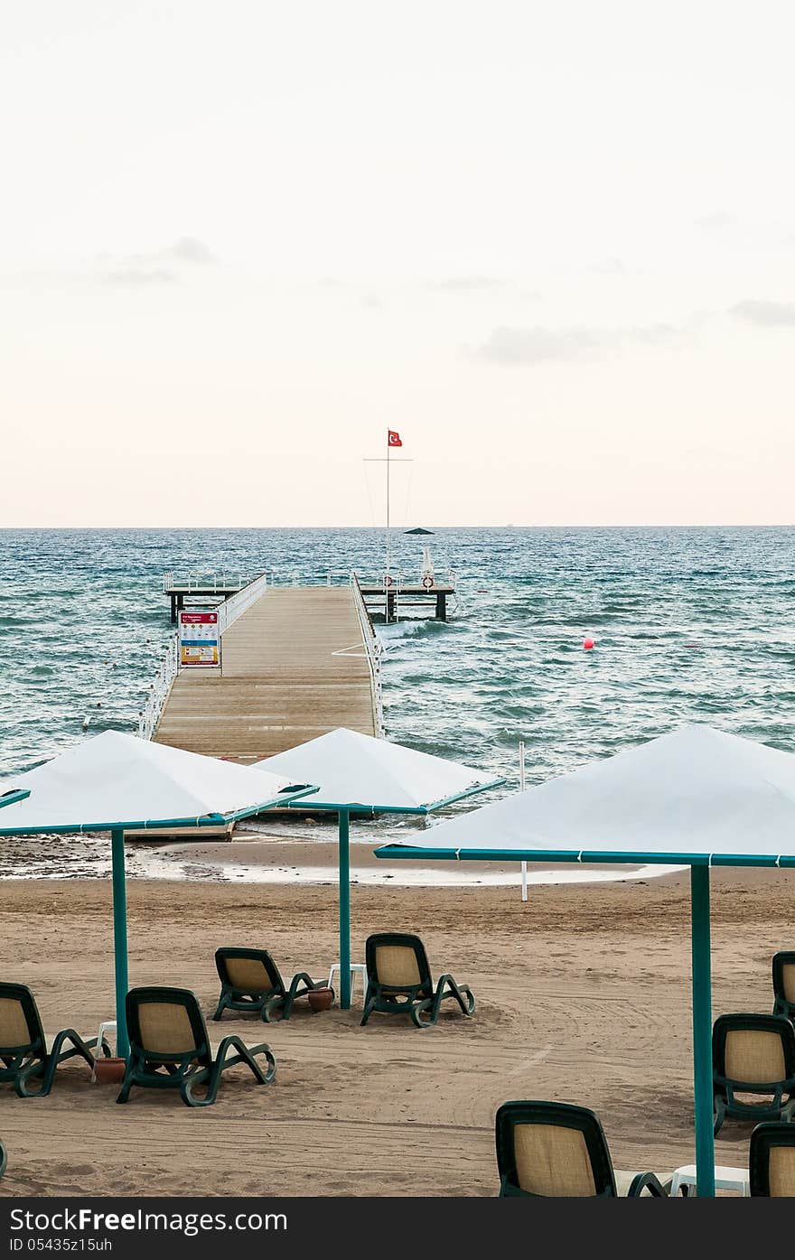 Beach in sunset with umbrellas and pier