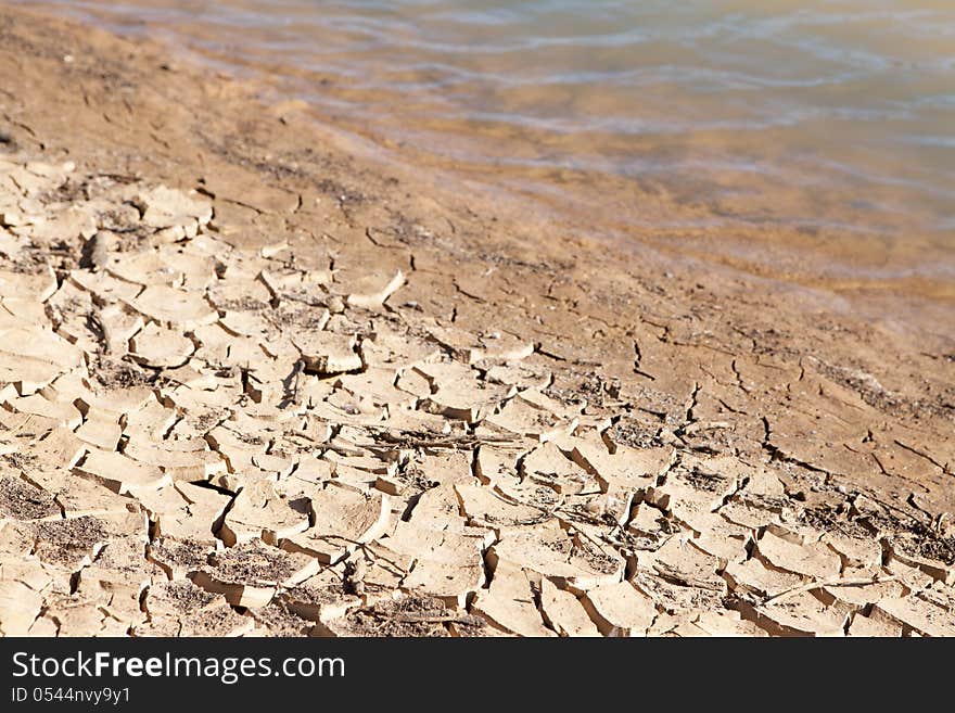 Contrast concept of dry cracked mud next to water