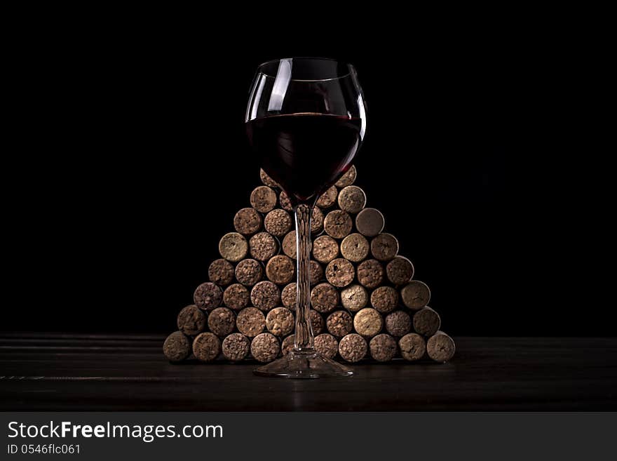 Glass with red wine against wine jams on a black background