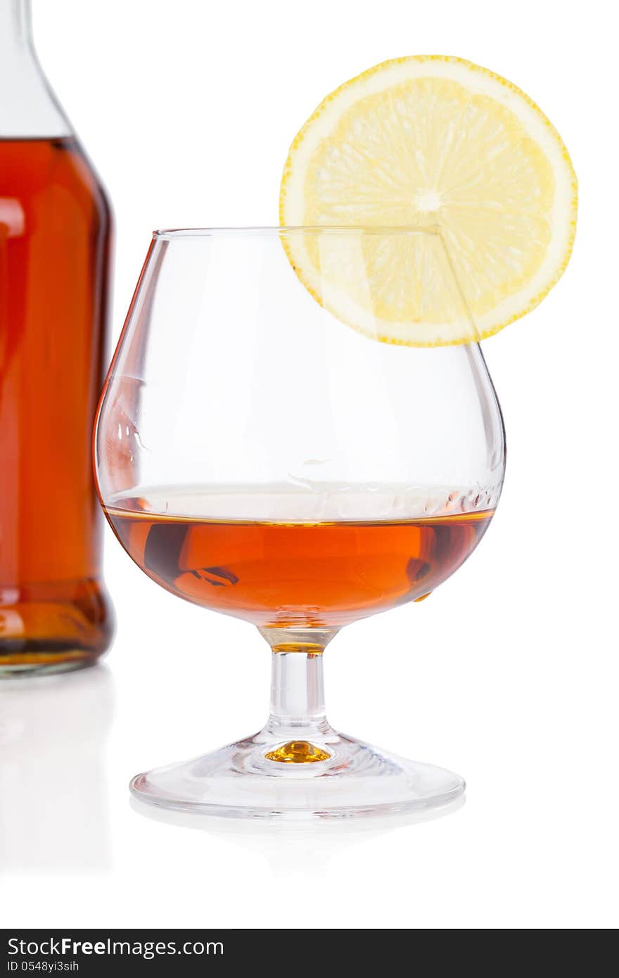 Glass of cognac with bottle on white background