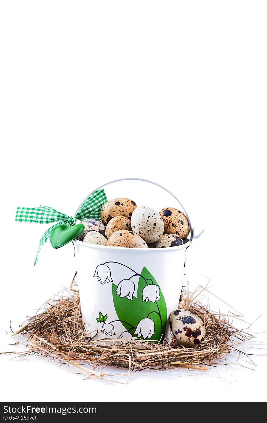 Quail eggs in a small bucket, standing on straw on white. Quail eggs in a small bucket, standing on straw on white