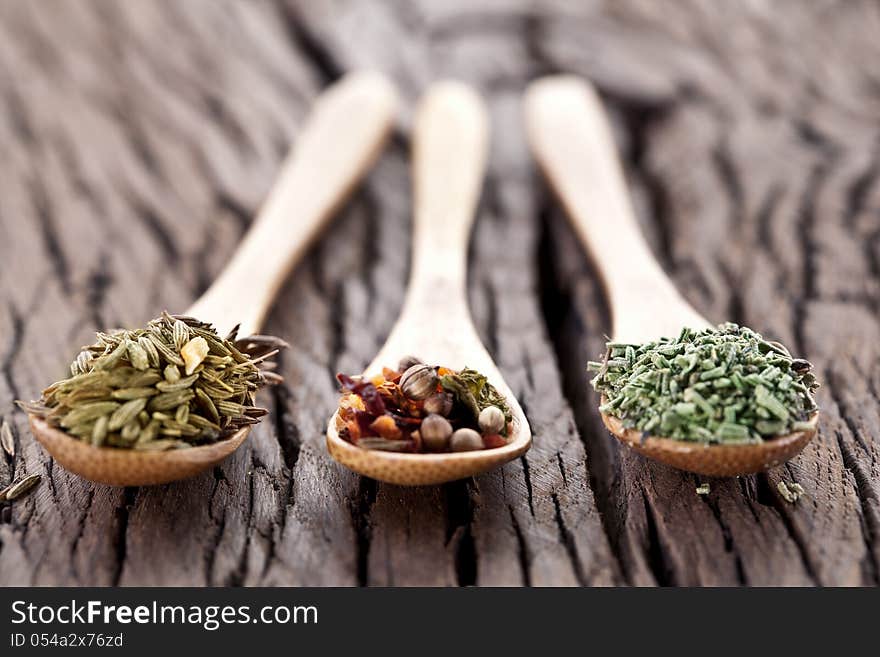 Variety of spices in the spoons on an old wooden table. Variety of spices in the spoons on an old wooden table.