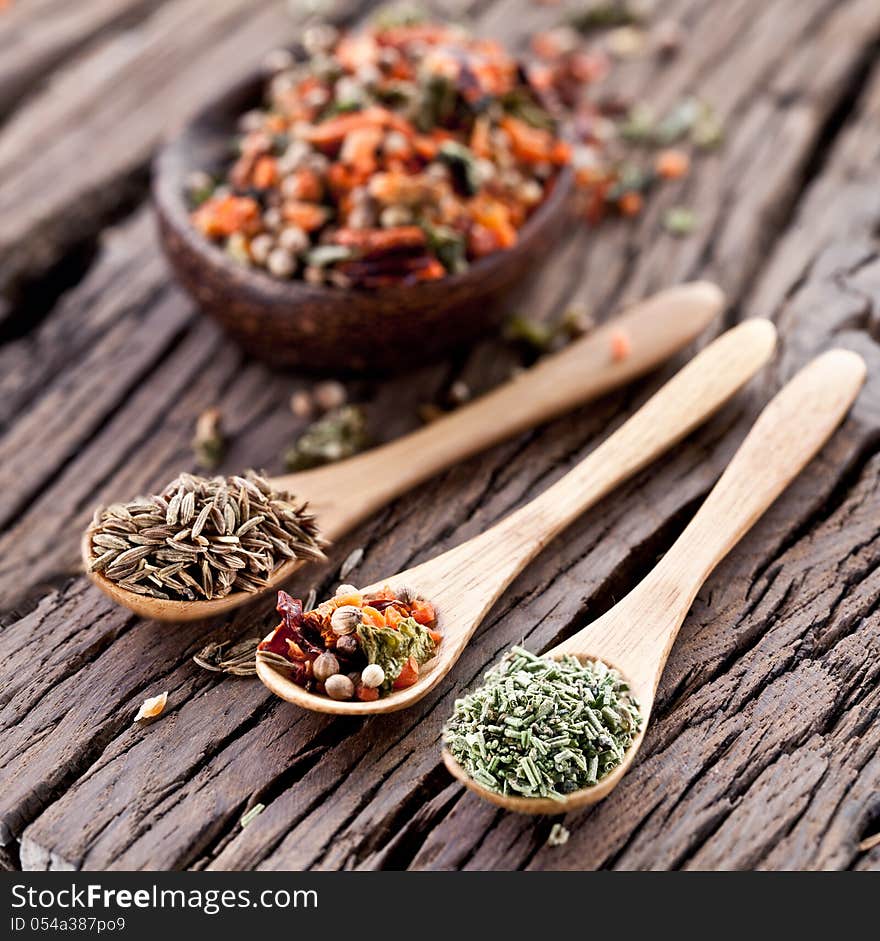 Variety of spices in the spoons on an old wooden table. Variety of spices in the spoons on an old wooden table.