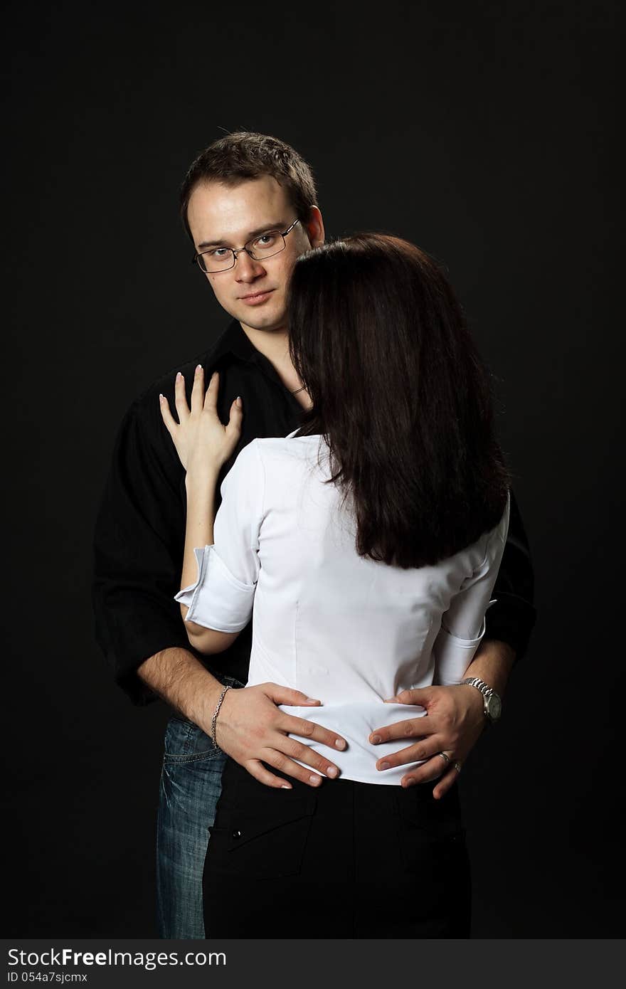 Young beautiful couple posing standing in studio on black background. Young beautiful couple posing standing in studio on black background