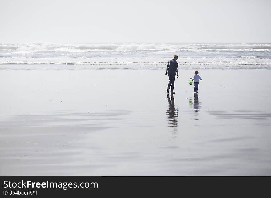 Mother and daughter walk on the beach out towards the Pacific Ocean. Mother and daughter walk on the beach out towards the Pacific Ocean.