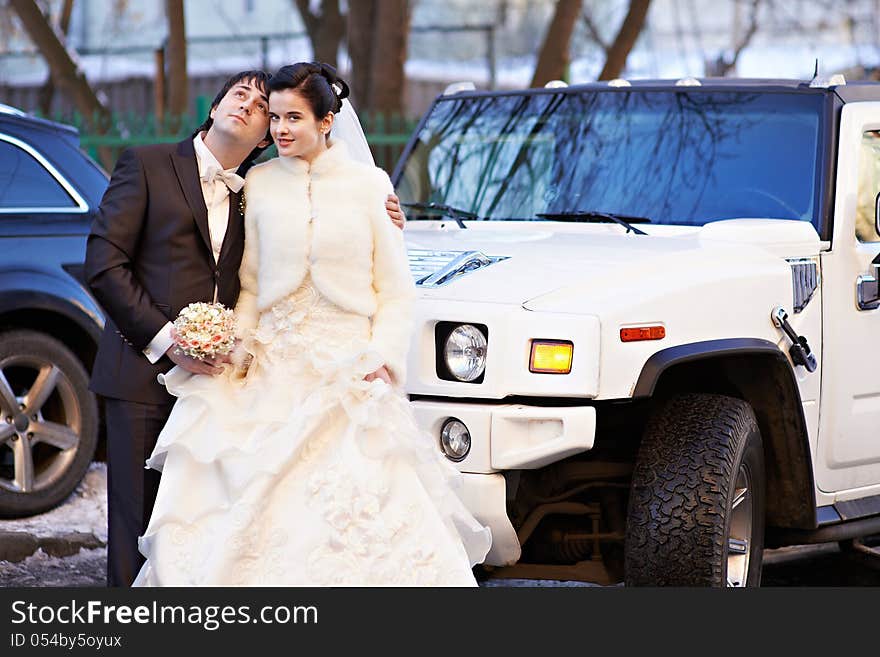 Happy bride and groom about wedding limousine in winter day