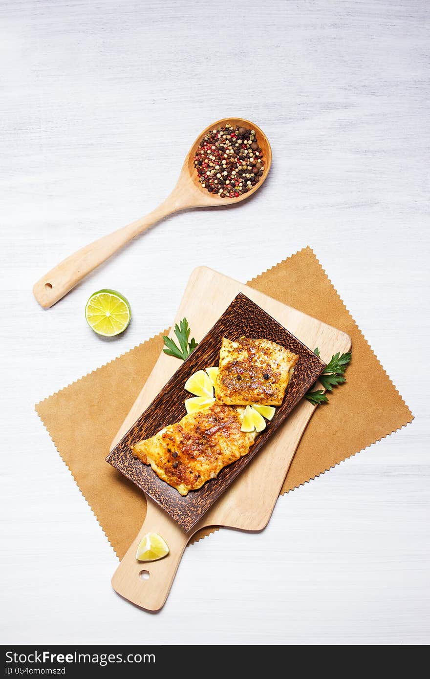 Fried white fish, served with lime, on wooden tableware