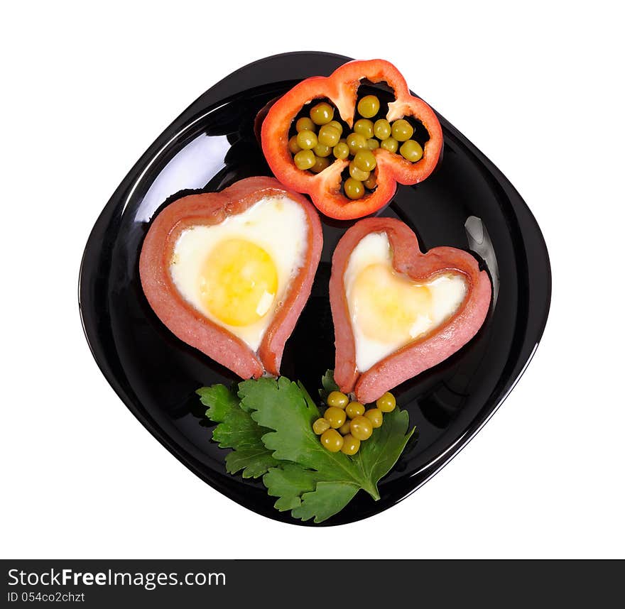 Sausages in the form of two hearts and fried eggs on a black plate isolated on white. Sausages in the form of two hearts and fried eggs on a black plate isolated on white