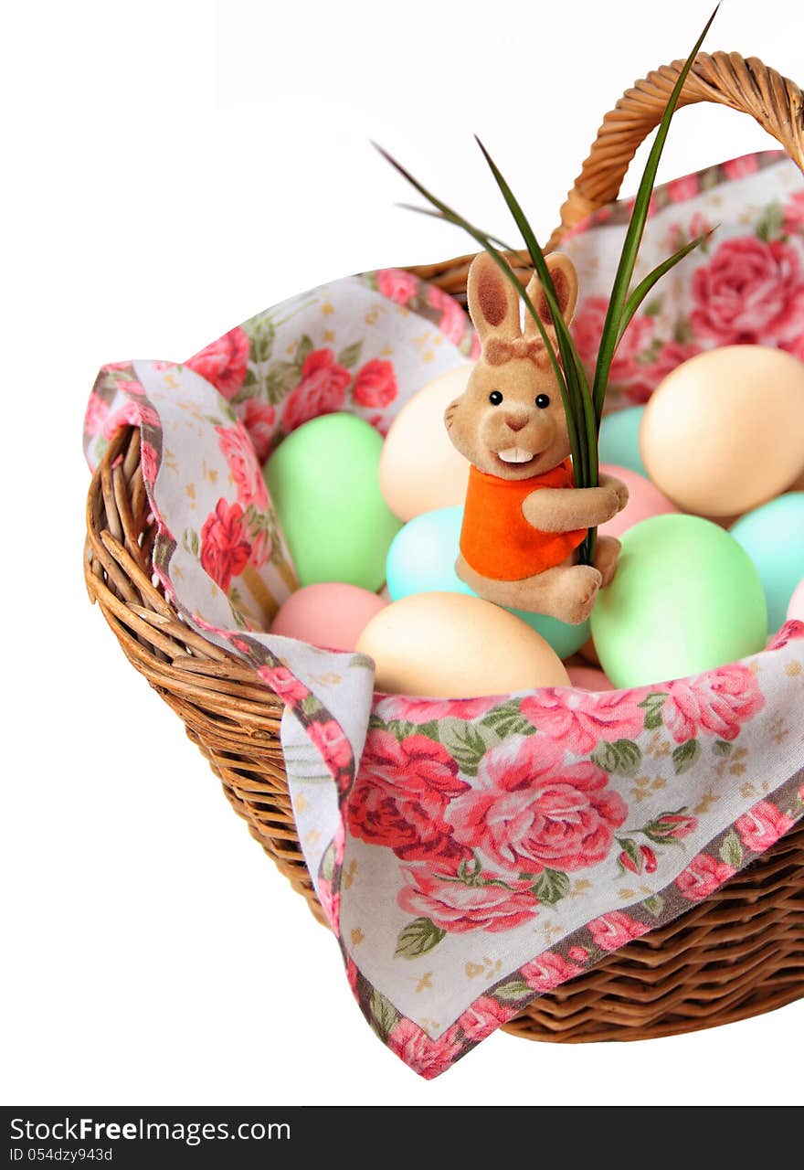 Easter Bunny sitting in a basket with colored eggs. Isolated on a white background.