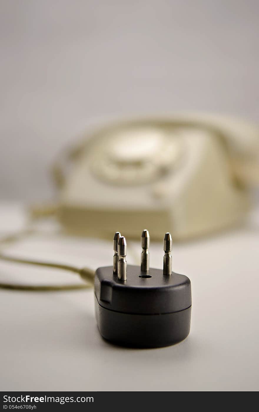 Unplugged classic gray / kaki telephone (T65 by PTT/Siemens) with rotary dial on white surface. Black connector unplugged. Unplugged classic gray / kaki telephone (T65 by PTT/Siemens) with rotary dial on white surface. Black connector unplugged.