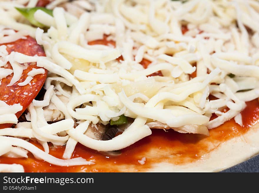 Pizza dough with tomato sauce, oregano, mushrooms, green pepper, pepperoni, ham and shredded mozzarella cheese. Pizza dough with tomato sauce, oregano, mushrooms, green pepper, pepperoni, ham and shredded mozzarella cheese