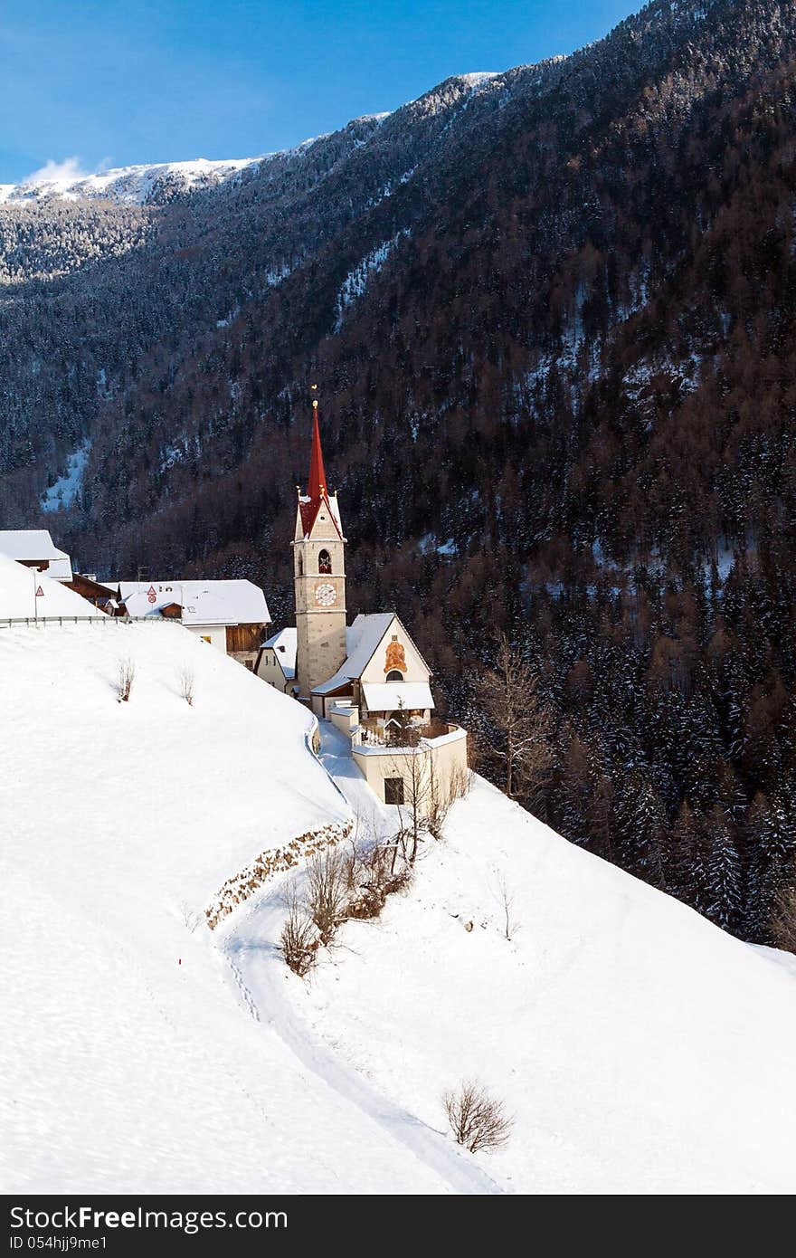 A wintertime view of a small church with a tall steeple in the Sud Tyrol, Italy.