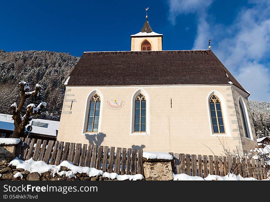 A wintertime view of a small church with a tall steeple