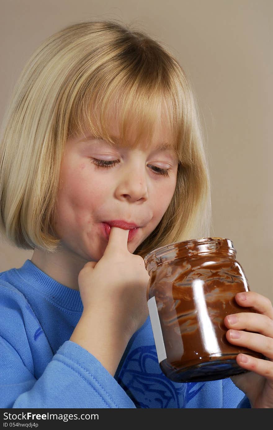 Little girl eating chocolate cream.Kid eating nut chocolate cream. Little girl eating chocolate cream.Kid eating nut chocolate cream.