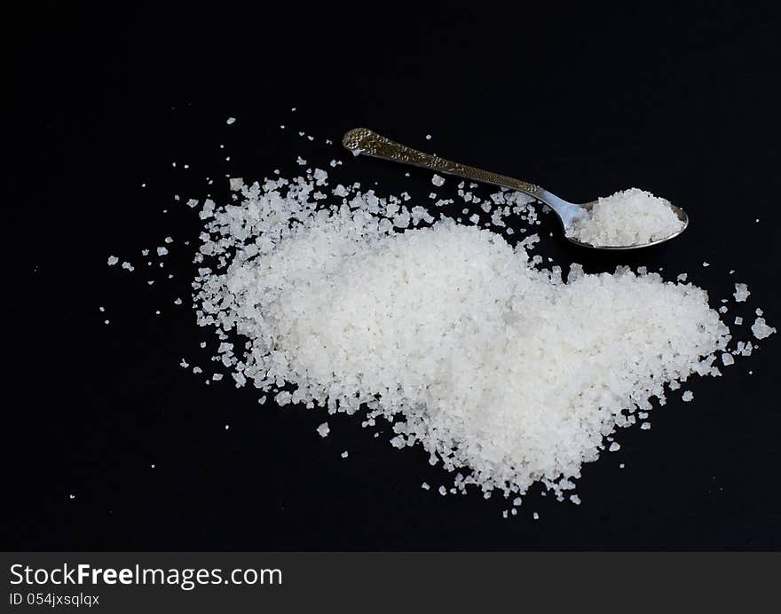 Salt on a black background with small spoon. Salt on a black background with small spoon