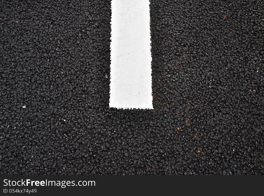 Closeup of a tar or asphalt pavement texture with a white line painted