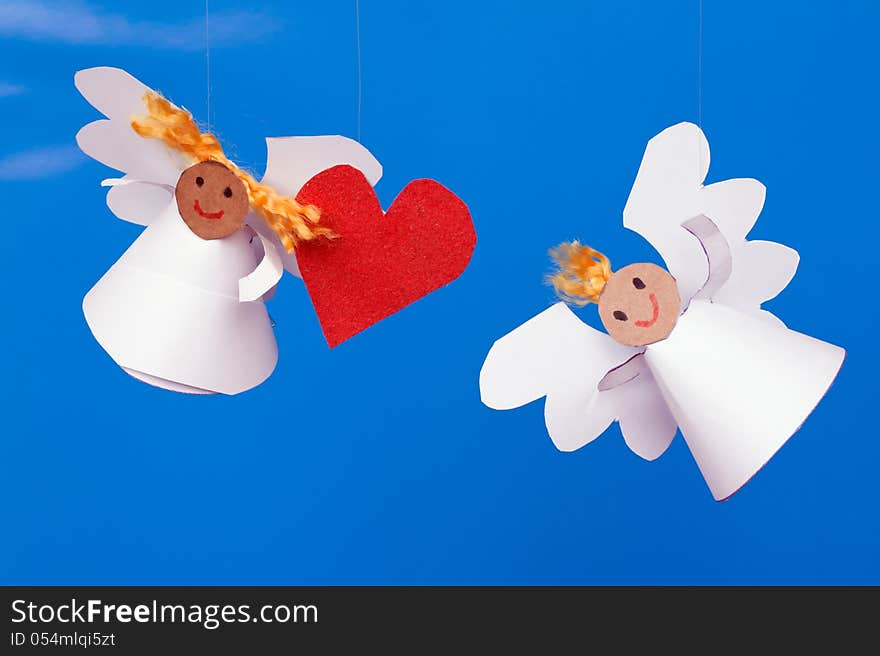 Two toy angel and a heart on a blue background. Two toy angel and a heart on a blue background