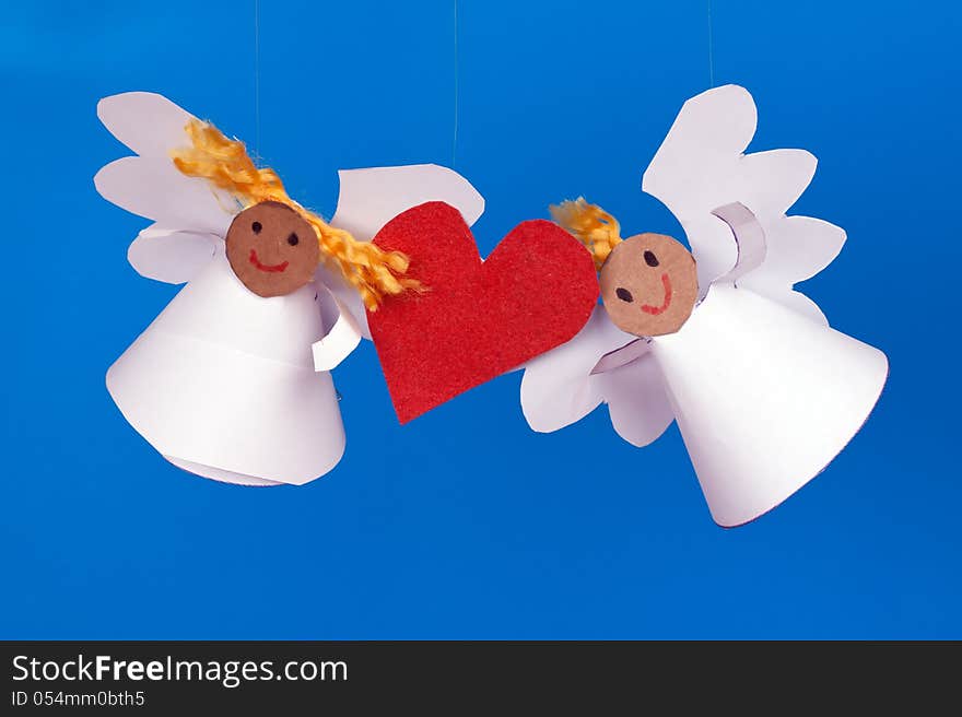 Two toy angel and a heart on a blue background. Two toy angel and a heart on a blue background