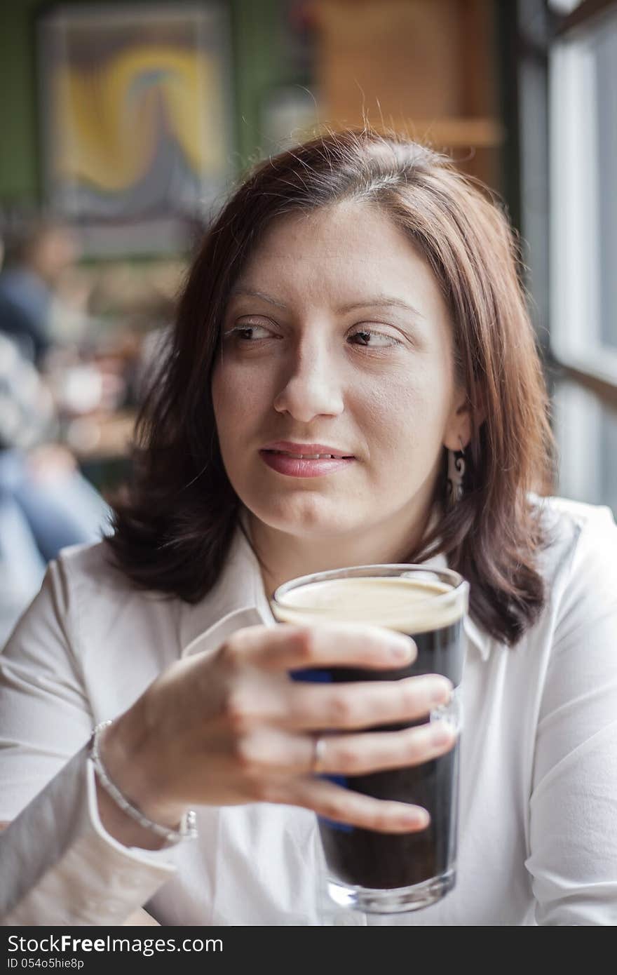 Portrait of a young woman drinking a pint of stout beer. Portrait of a young woman drinking a pint of stout beer.