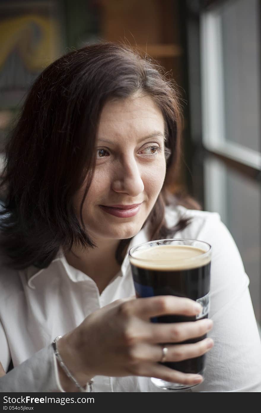 Young Woman with Beautiful Brown Eyes Drinking a Pint of Stout