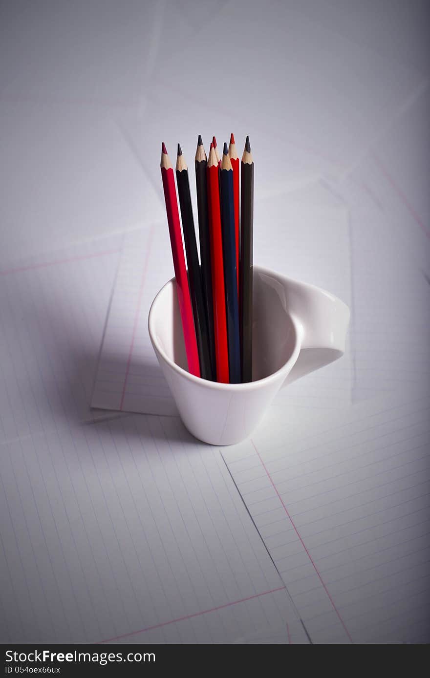 Black and red pencils stand in a white mug