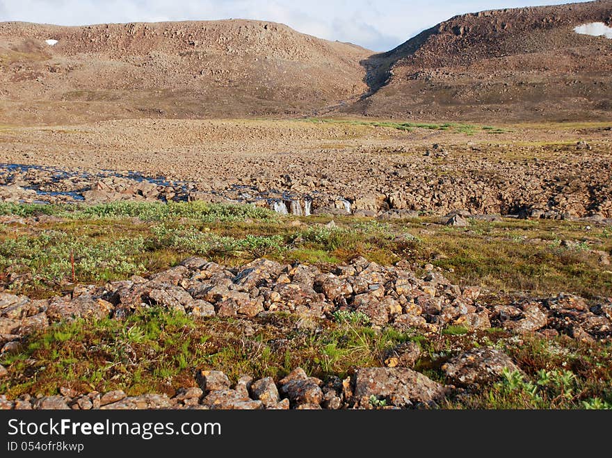 A Rocky Landscape With A Waterfall.